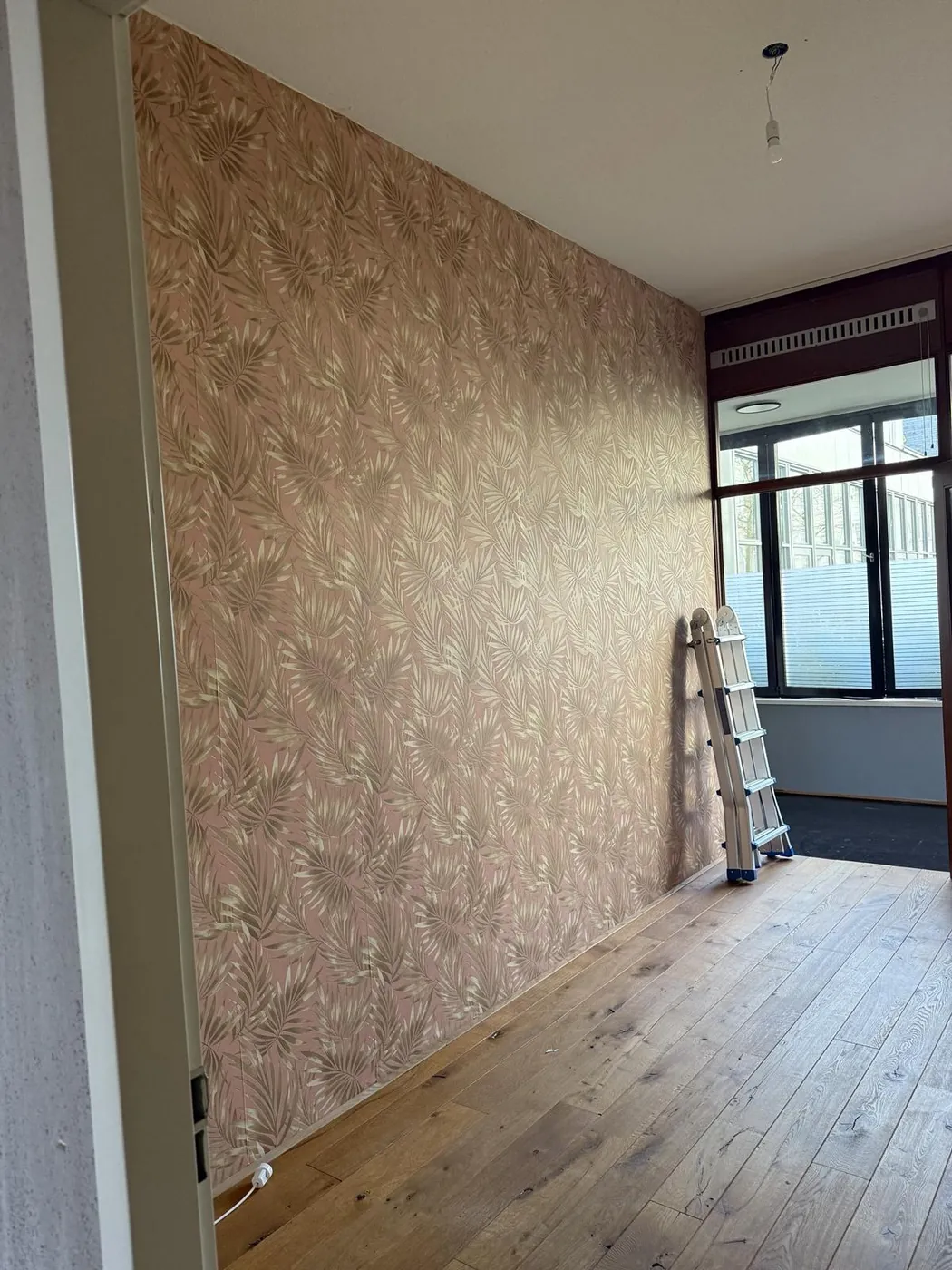 Muur met behang in een appartement vóór het schilderwerk