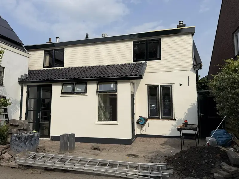 Witte achtergevel van een woning met zwarte kozijnen en pannendak