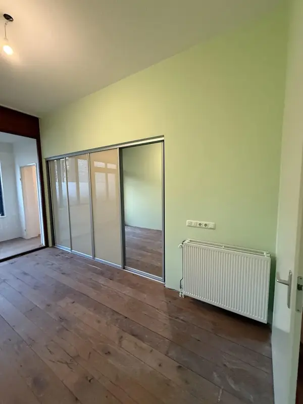 Kamer met een strak groen geschilderde wand en schuifdeuren