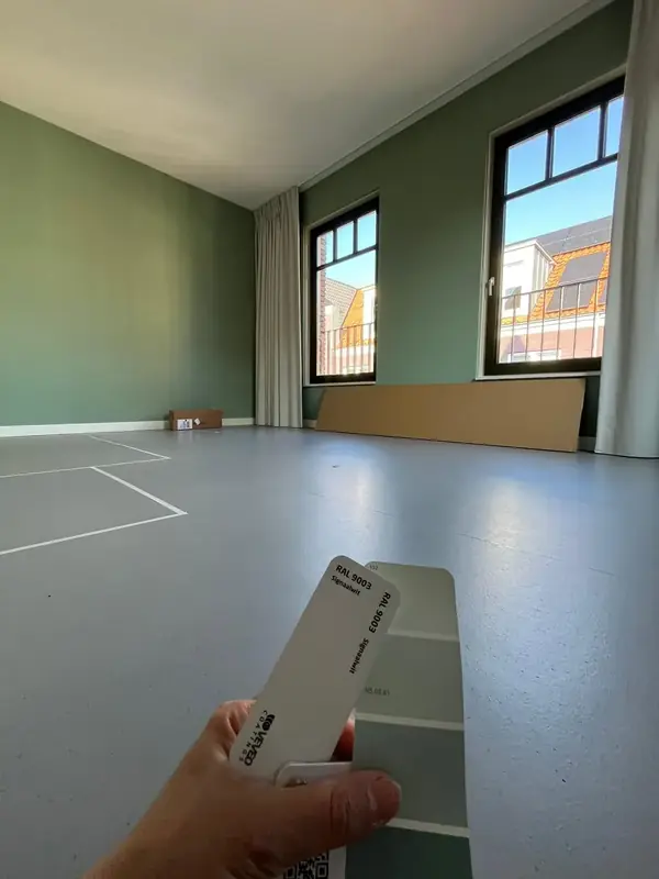 Ruime kamer met een groen geschilderde muur en een kleurenwaaier in beeld